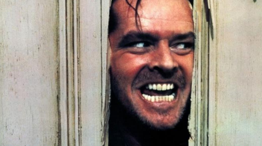 Jack Nicholson in The Shining, grinning through a hole he has smashed in a door
